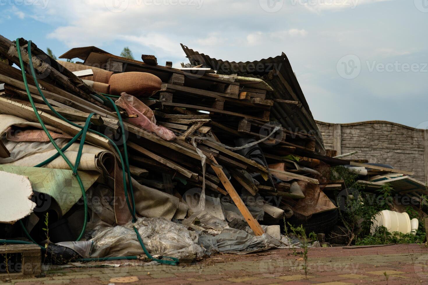 A mountain of large, household garbage lies on the ground near the fence photo