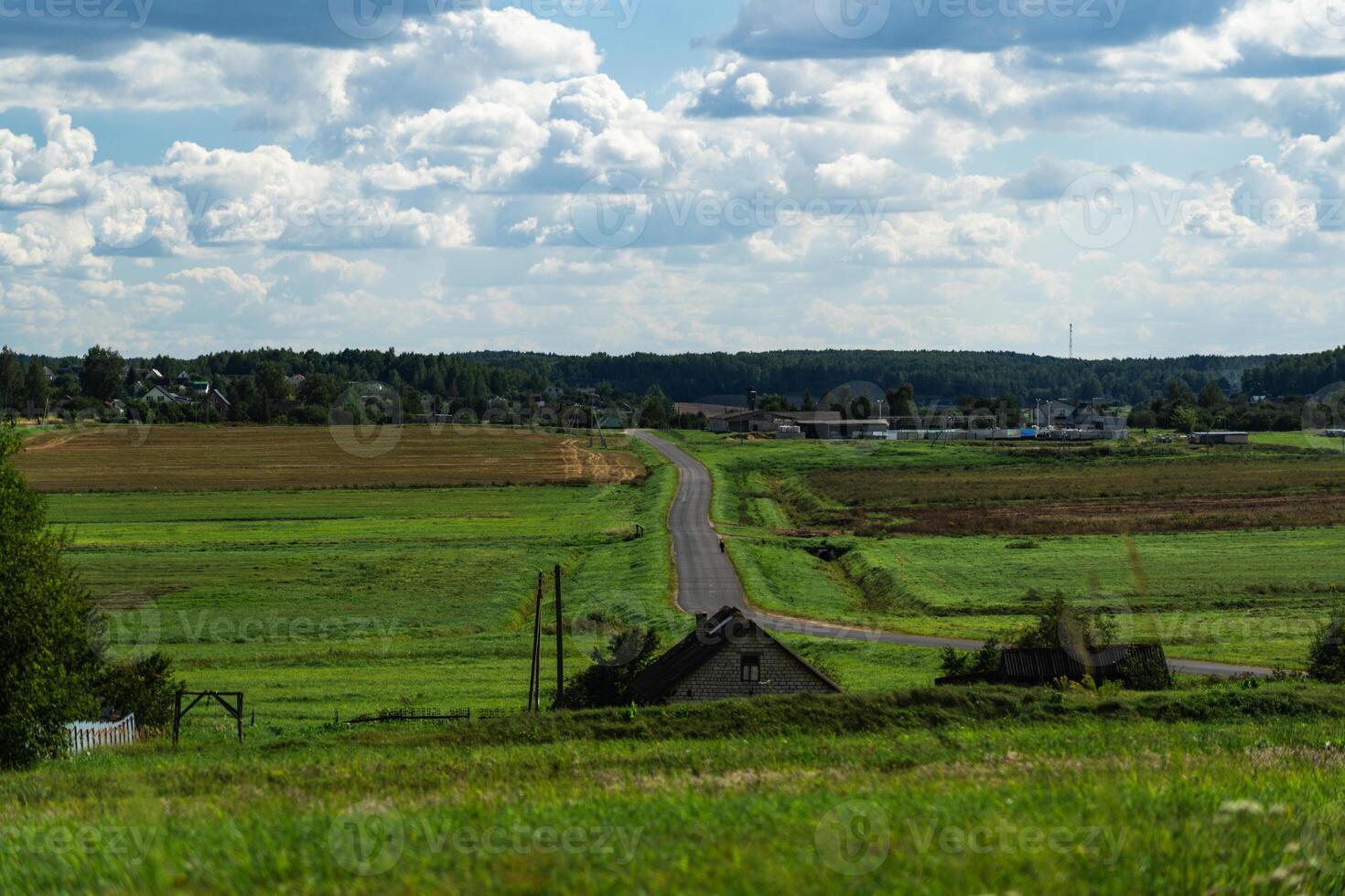 An asphalt road in the distance between fields. Thick clouds over the road photo