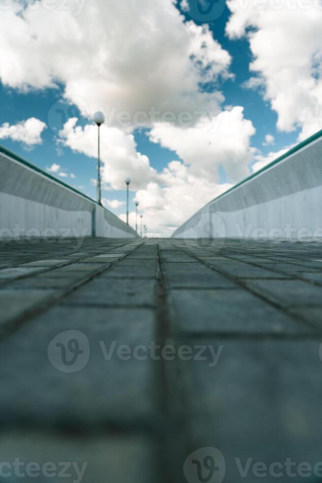 Paving slabs on a pedestrian bridge. The bridge is nearby. Clouds in the sky photo