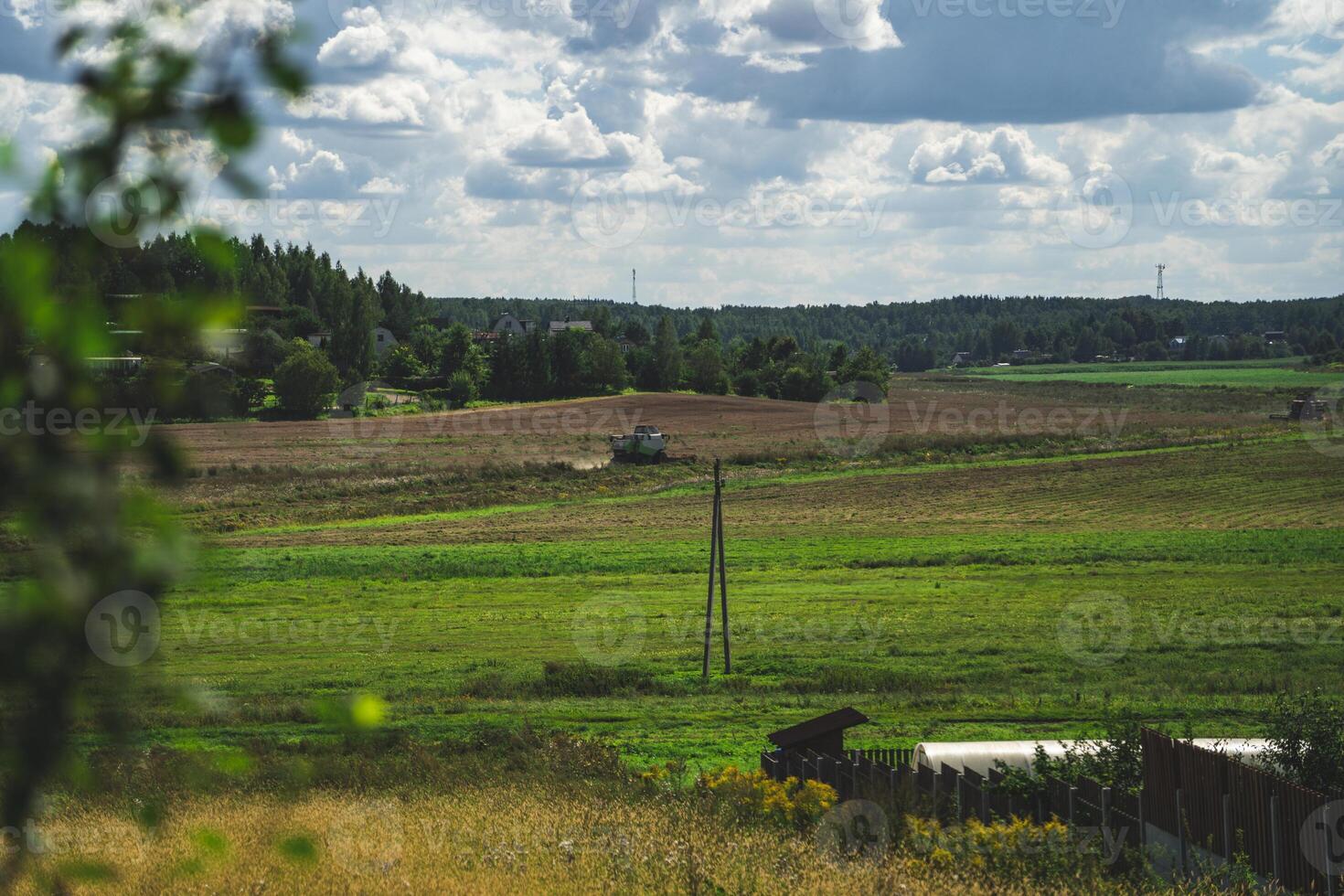 A combine harvester in the distance reaps wheat in a field photo