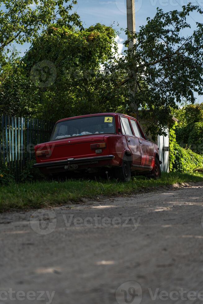A red Soviet car is parked on the side of the road in the village photo