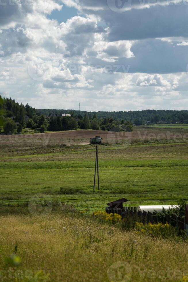 A combine harvester in the distance reaps wheat in a field photo