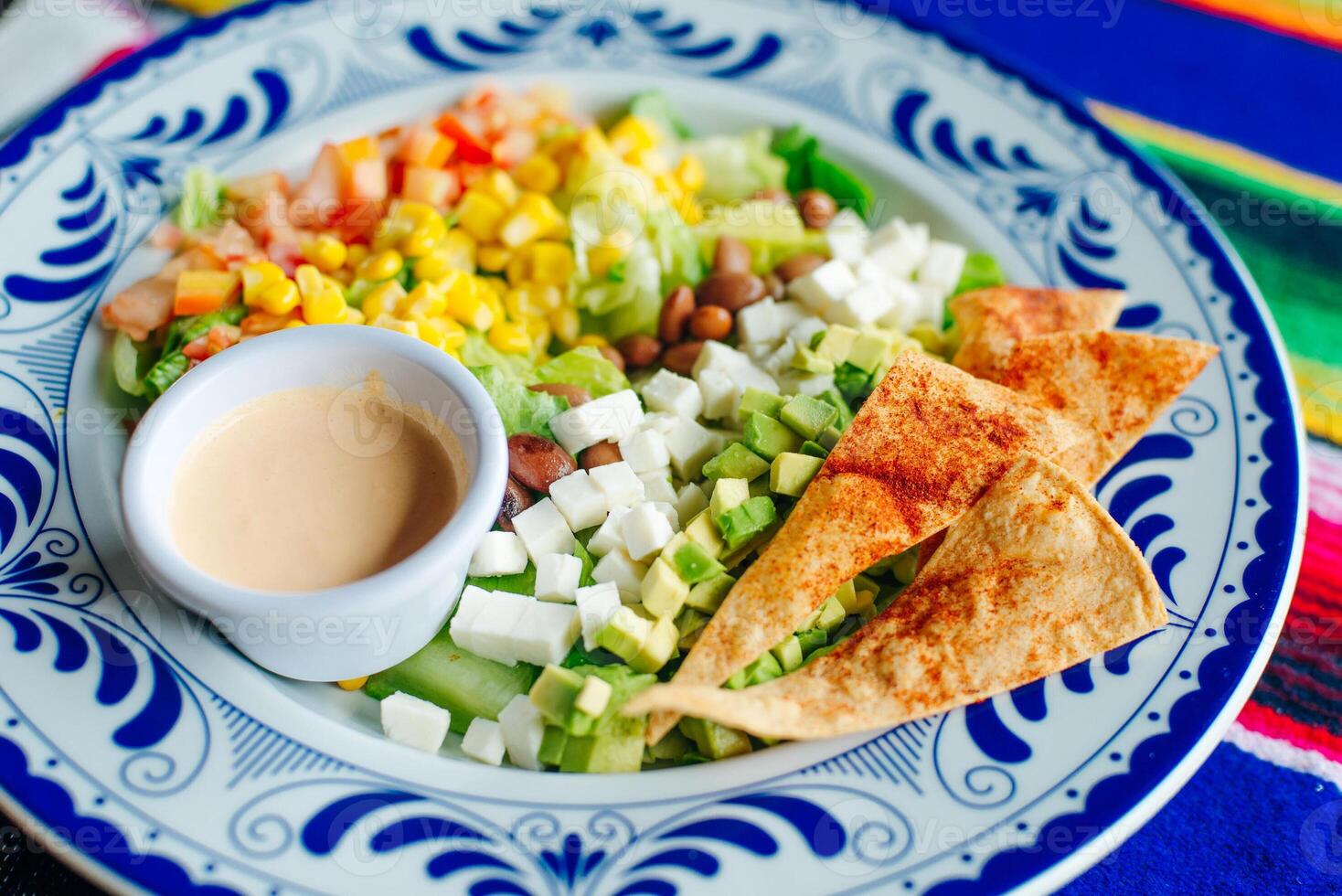 mexican salad with corn, pepper, chips, cheese, avocado and sauce photo