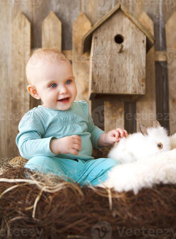 Portrait of an adorable baby girl and little white rabbit. Easter concept photo