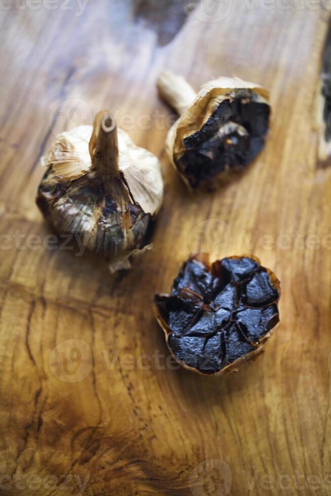 Black garlic bulbs and cloves on wooden background photo