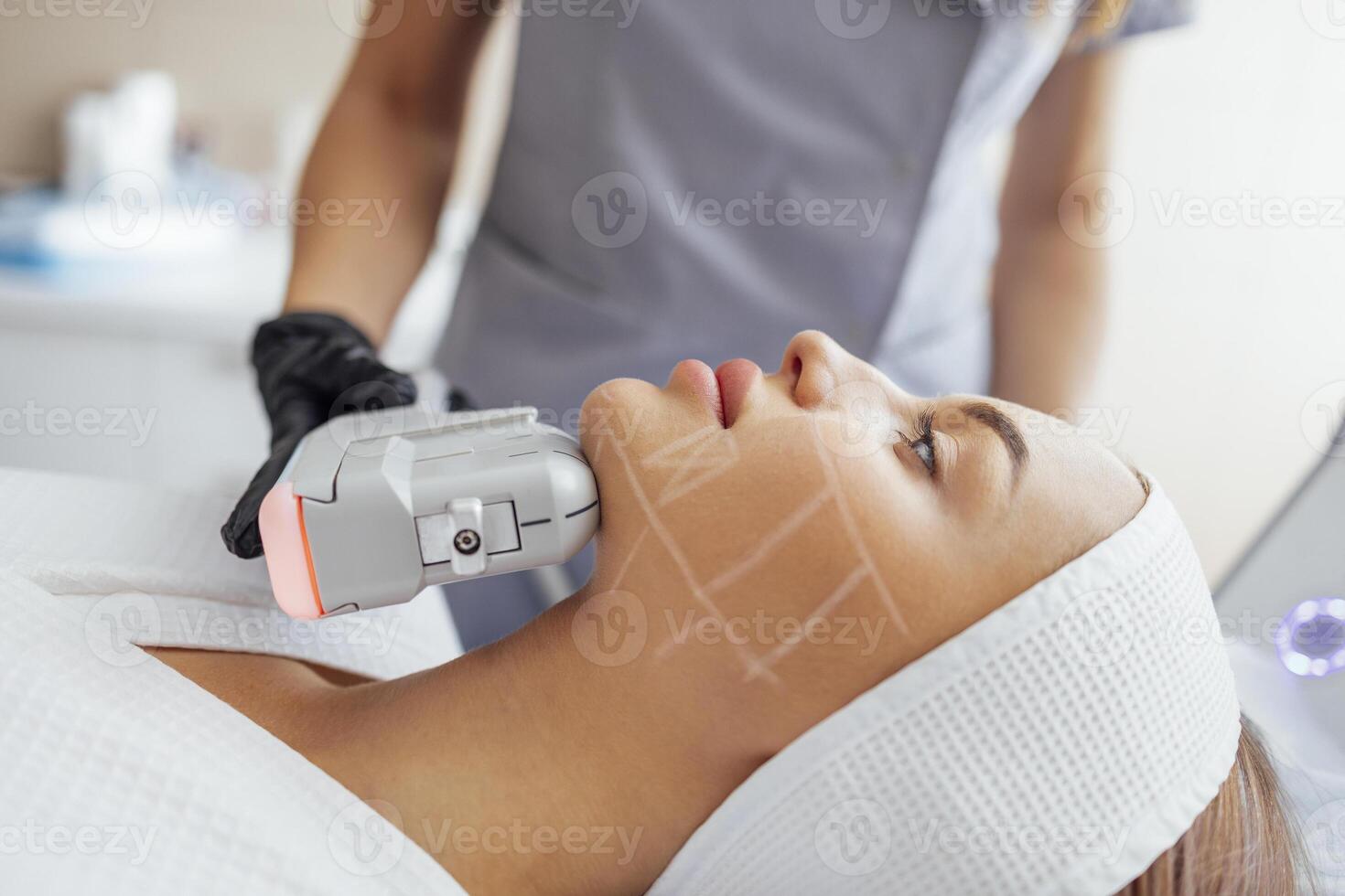 Portrait of relaxed young female client getting SMAS ultrasound face lifting massage photo