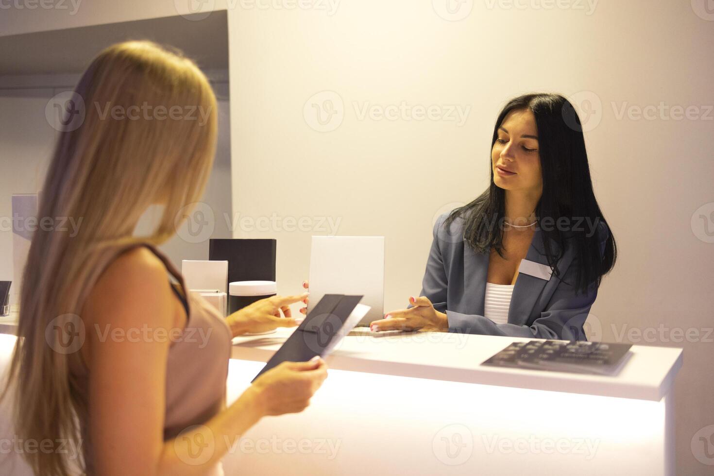 Smiling female client communicates with reception woman in a beauty salon photo