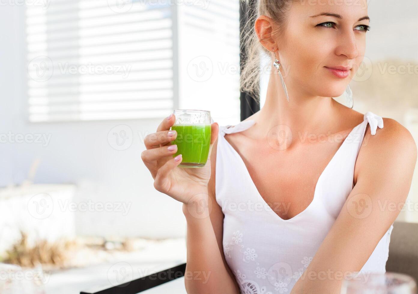 Woman holding glass of a green juice in her hand photo
