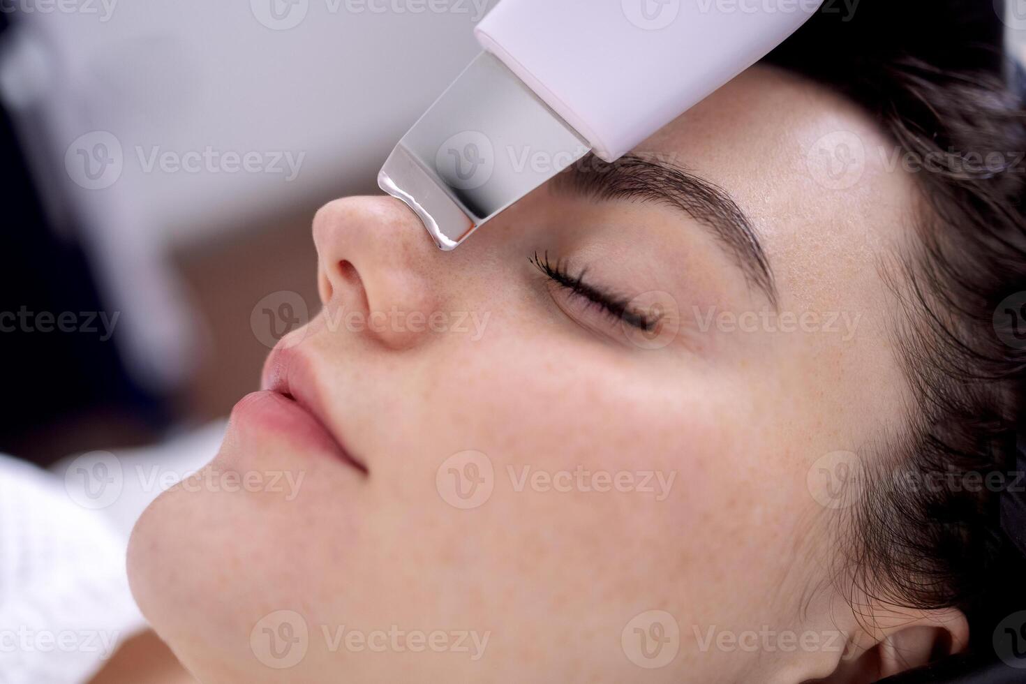 Beauty master makes ultrasonic facial peeling to her client. photo