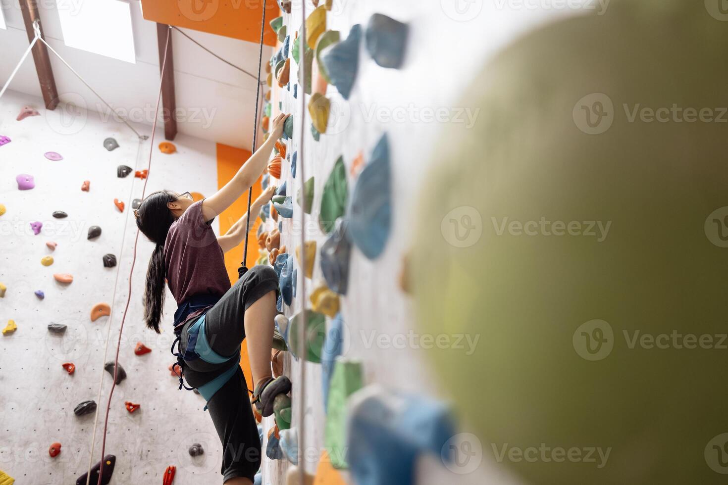 A young Asian woman on a climbing wall. A Korean girl climbs a bouldering wall photo