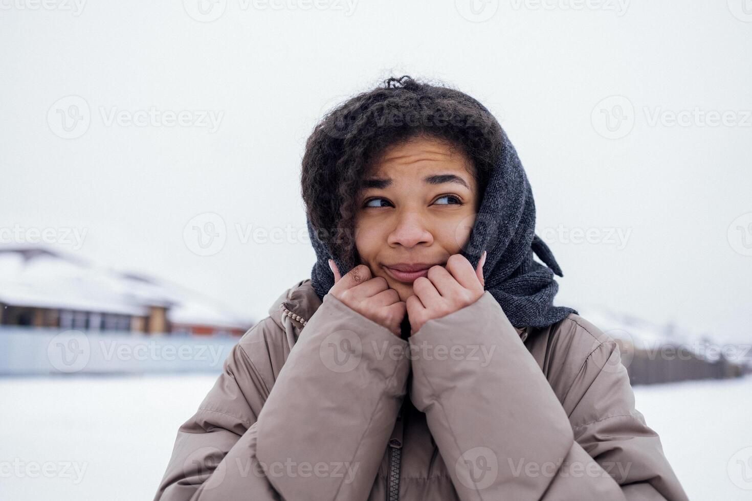 Close up of beautiful mixed race girl feels cold and wraps herself up in knitted woolen scarf. photo