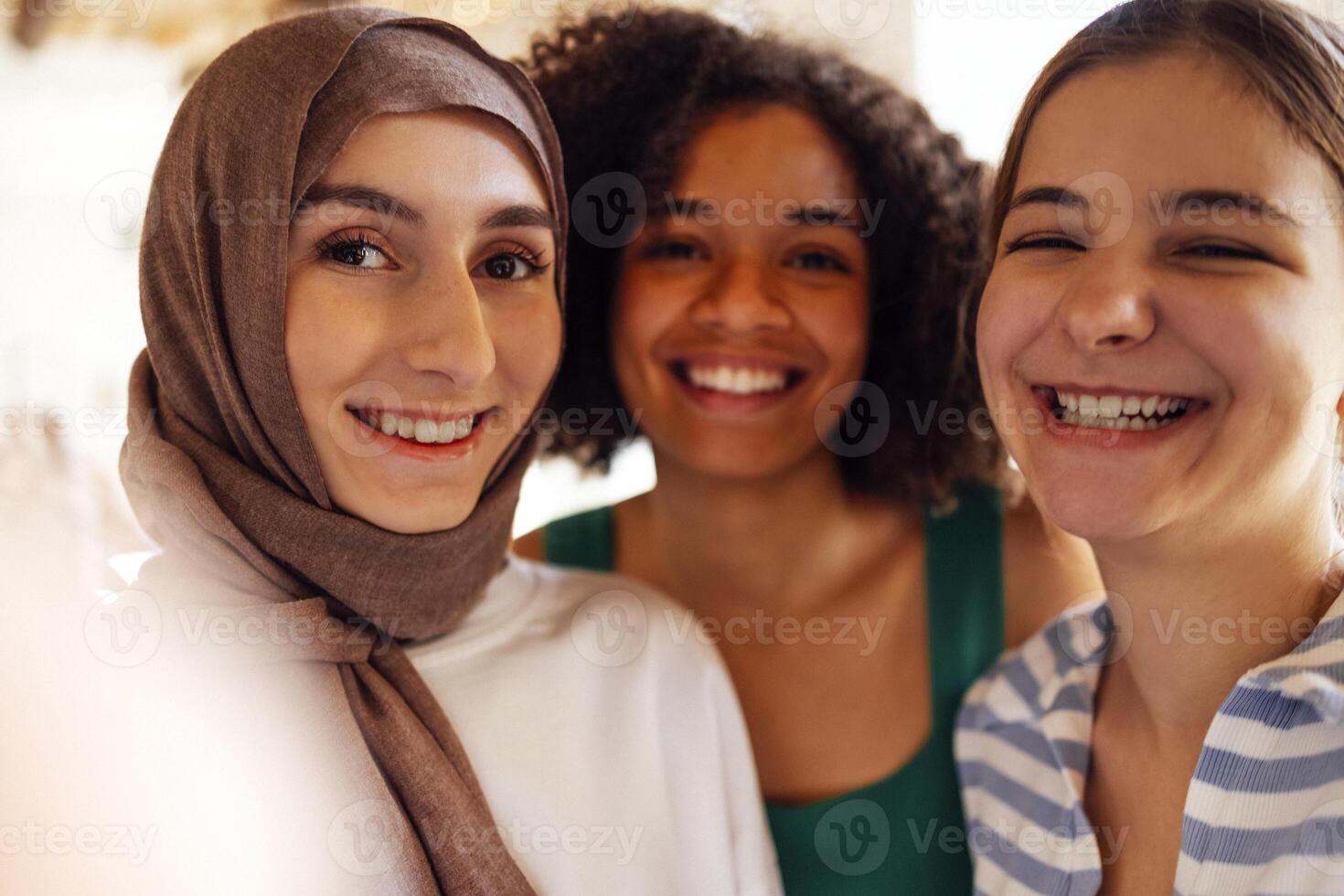 Close up portraits of three smiling teenage girls. Muslim in a hijab, african american and white friends females. photo