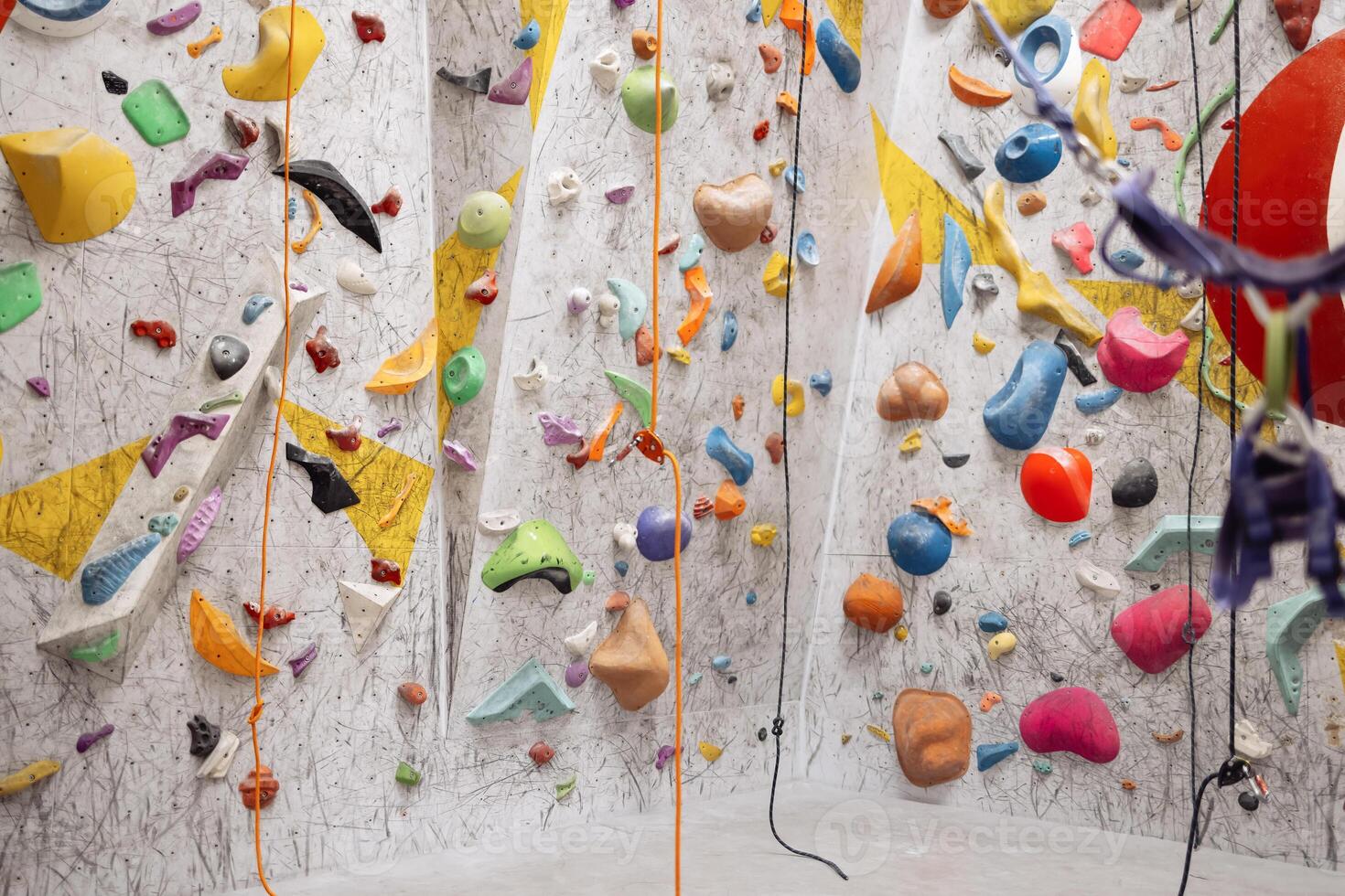 Interior shot of indoor climbing centre without people with assortment of colorful and challenging climbing walls. White wall with climbing holds in gym. photo