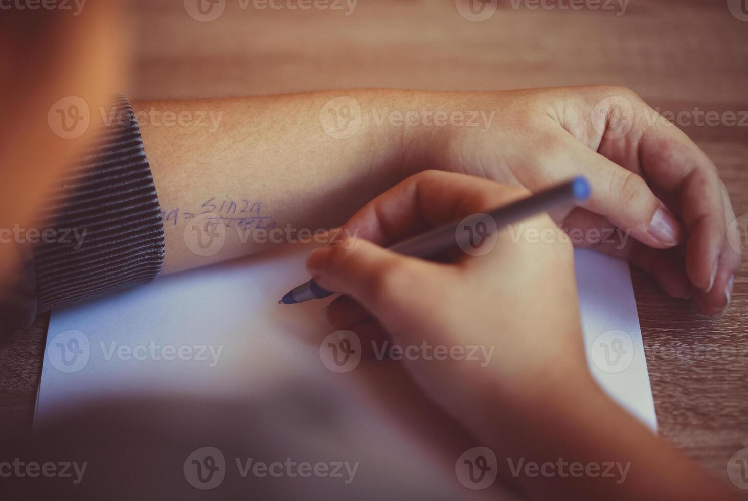 Student cheating during exam in university, reading cheat sheet with formula written on hand photo