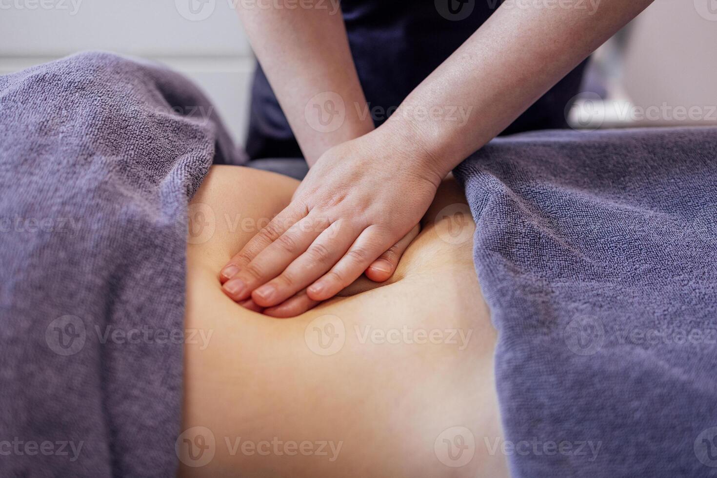 Close up of young female hands doing belly massage in a beauty salon or clinic. photo