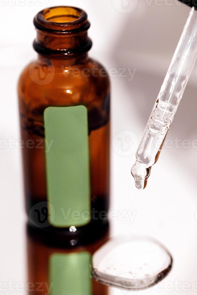 Close up of brown serum or oil glass with green stiker mock up on bottle on mirror background photo