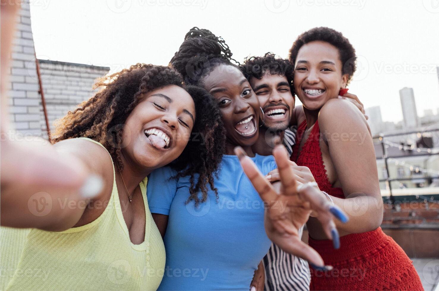 Four smiling mixed race friends standing and looking down at camera photo