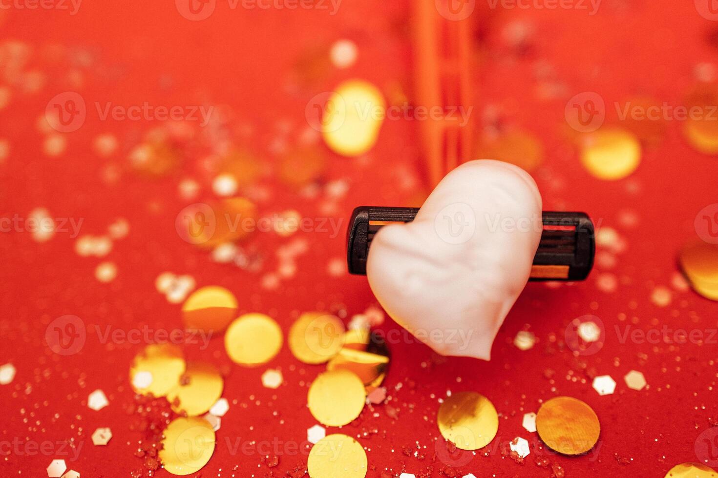 Razor with heart shaped shaving foam. Bright red background with silver glitters and gold round confetti. photo