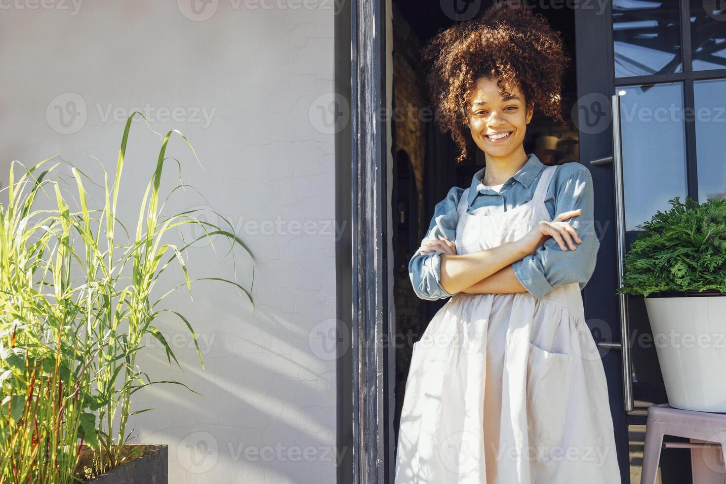 Cheerful young pretty female barista standing at the door photo