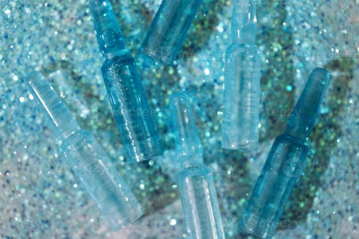 Blue ampoules with intense moisturizing concentrate with hyaluronic acid and vitamins on shiny sparkling background. photo
