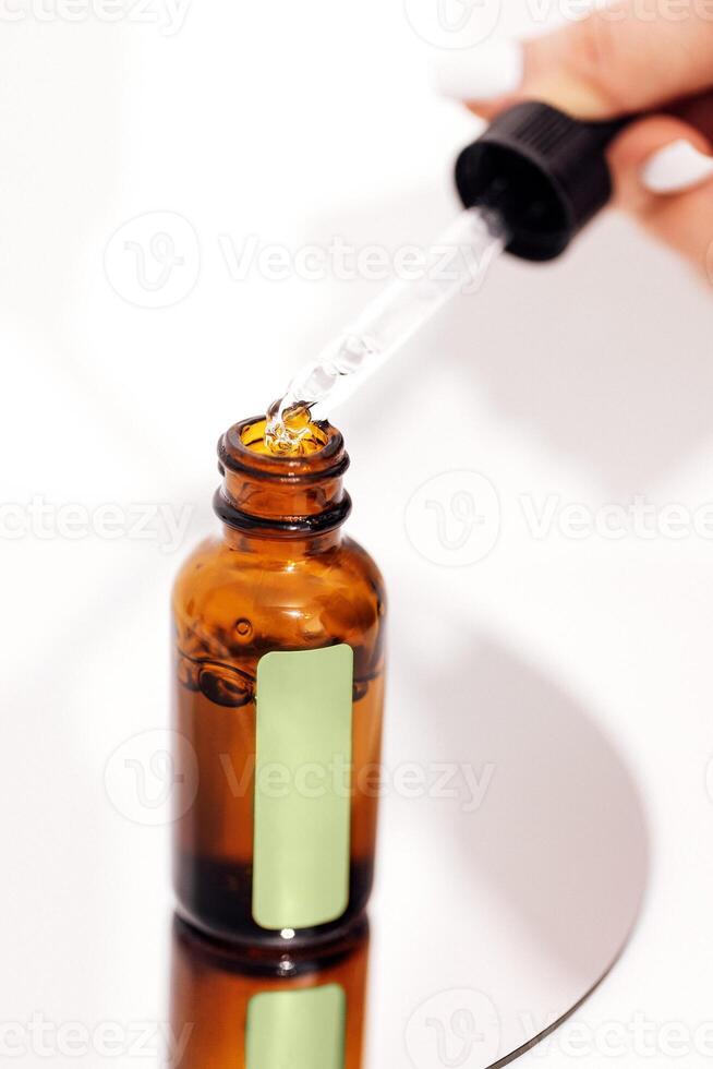 a person is pouring a bottle of essential oil into a glass bottle photo