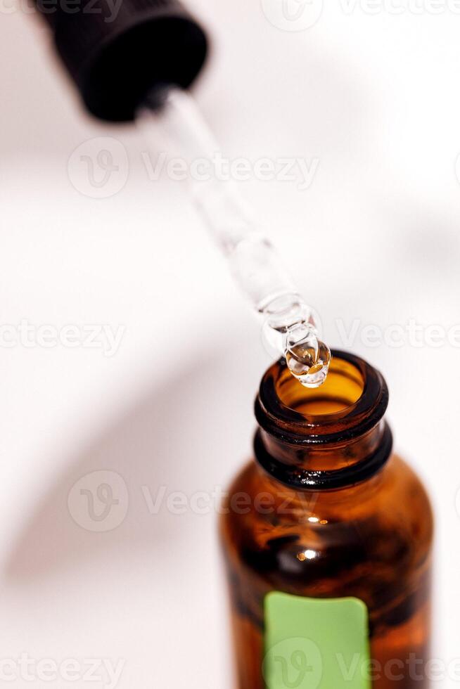 Close up of brown serum or oil glass with green stiker mock up on bottle on mirror background photo