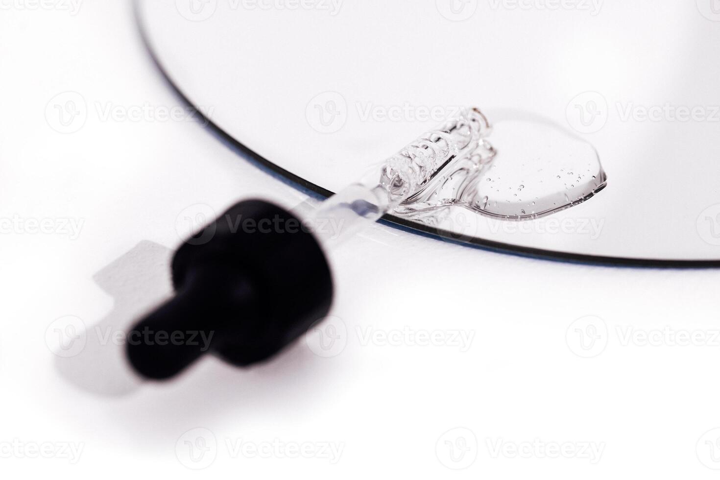Close up of gel or serum glass pipette with transparent drops on white background. photo