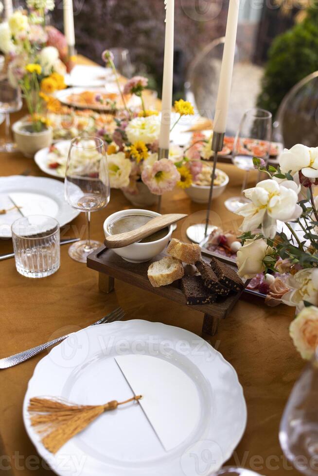 Wedding table for guests, decorated with candles, are served with cutlery and crockery and covered with yellow tablecloth photo