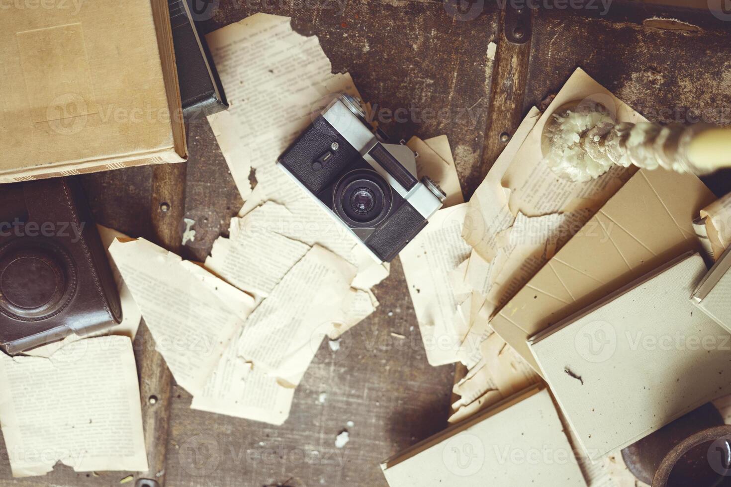 Retro background with vintage camera, case, old books, torn sheets of paper and a candle with melted wax drops. photo