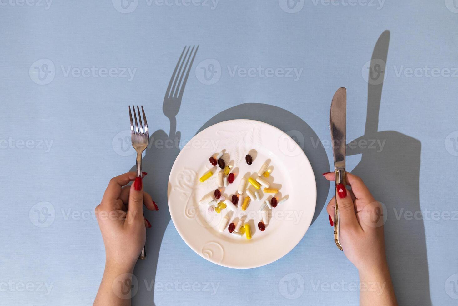 Tablets, pills and capsules on a white porcelain plate. The table is set with a plate photo