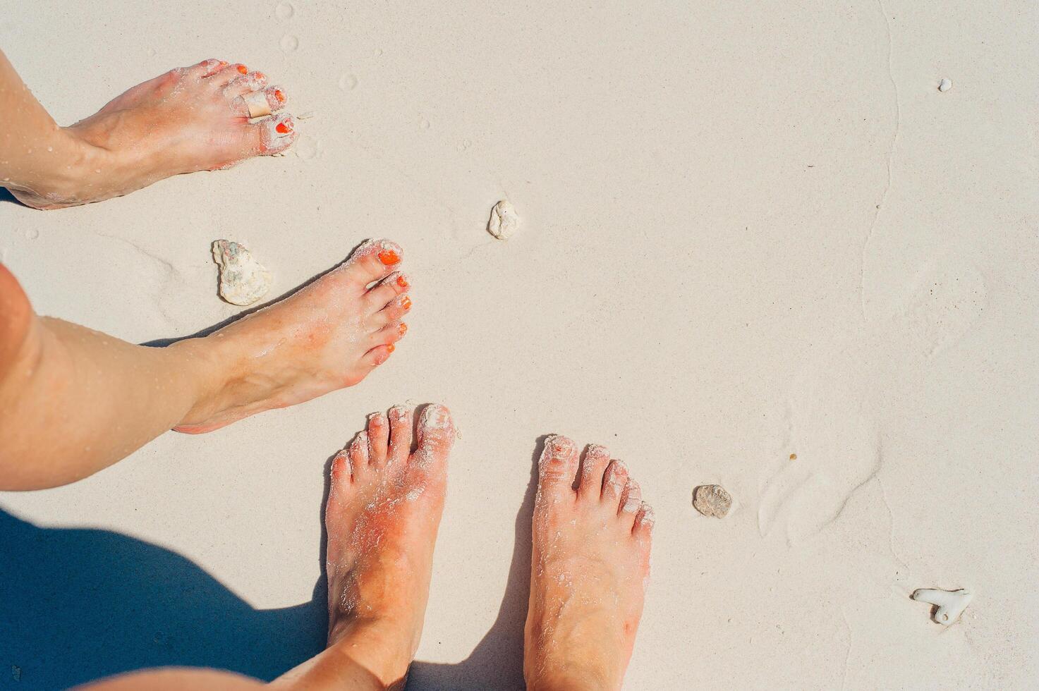 Young woman looking down of view perspective on bare feet standing in white sand photo