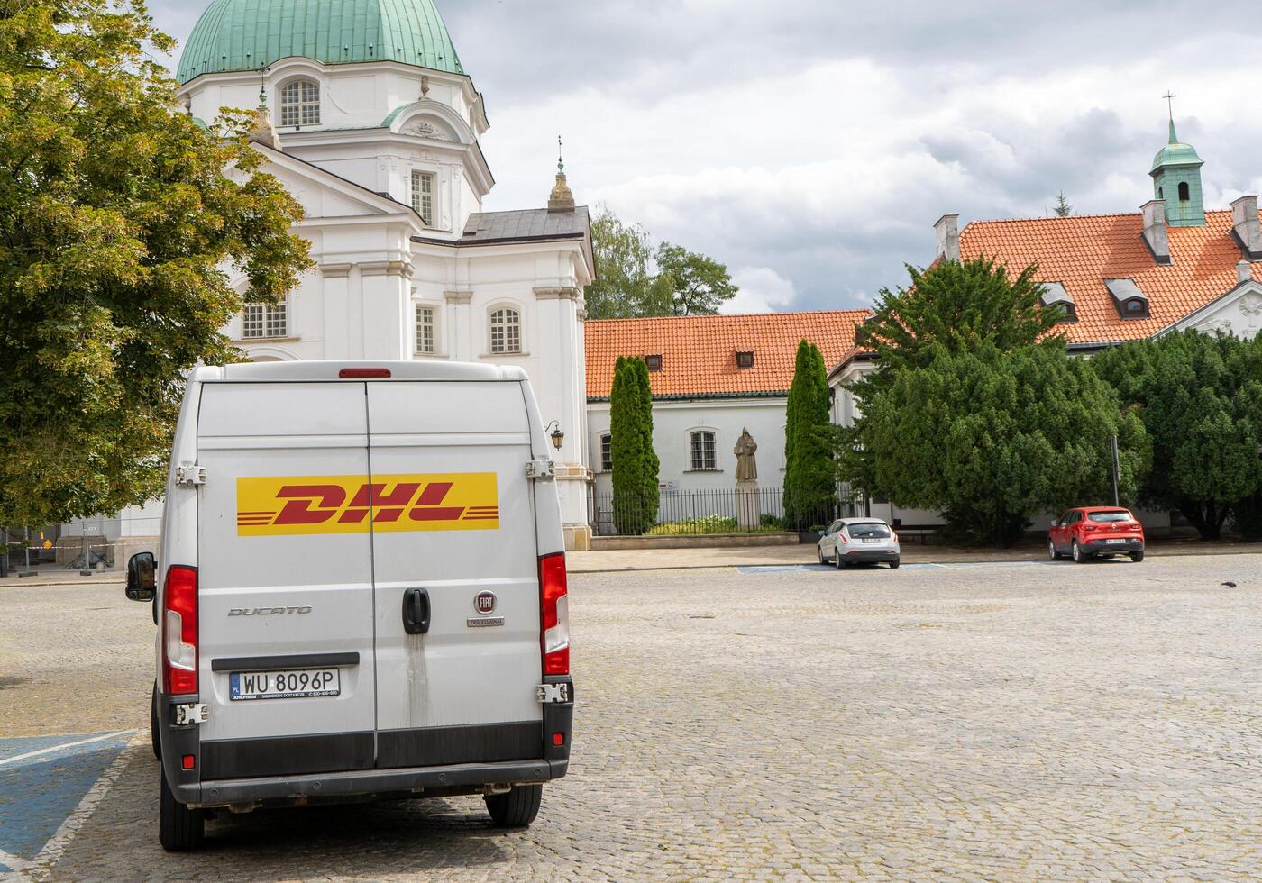 Delivery by DHL. White minibus on the street, delivery of settlements and documents. Poland, Warsaw - July 26, 2023 photo