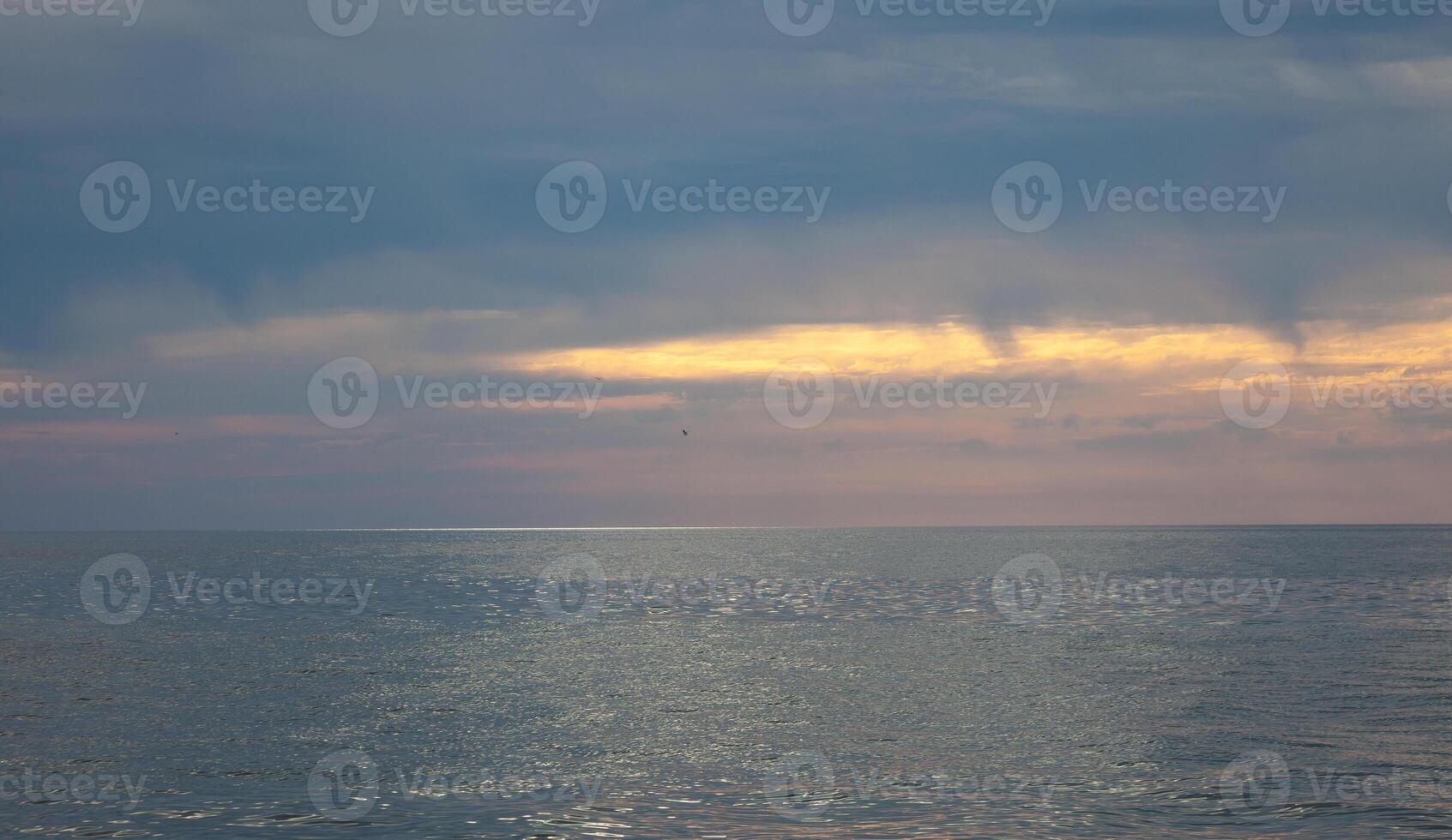 Seascape. Waves and surf. Sunset and dawn at sea. Calm on the ocean. Beautiful sky and clouds illuminated by the sun. Natural background. Summer time. photo