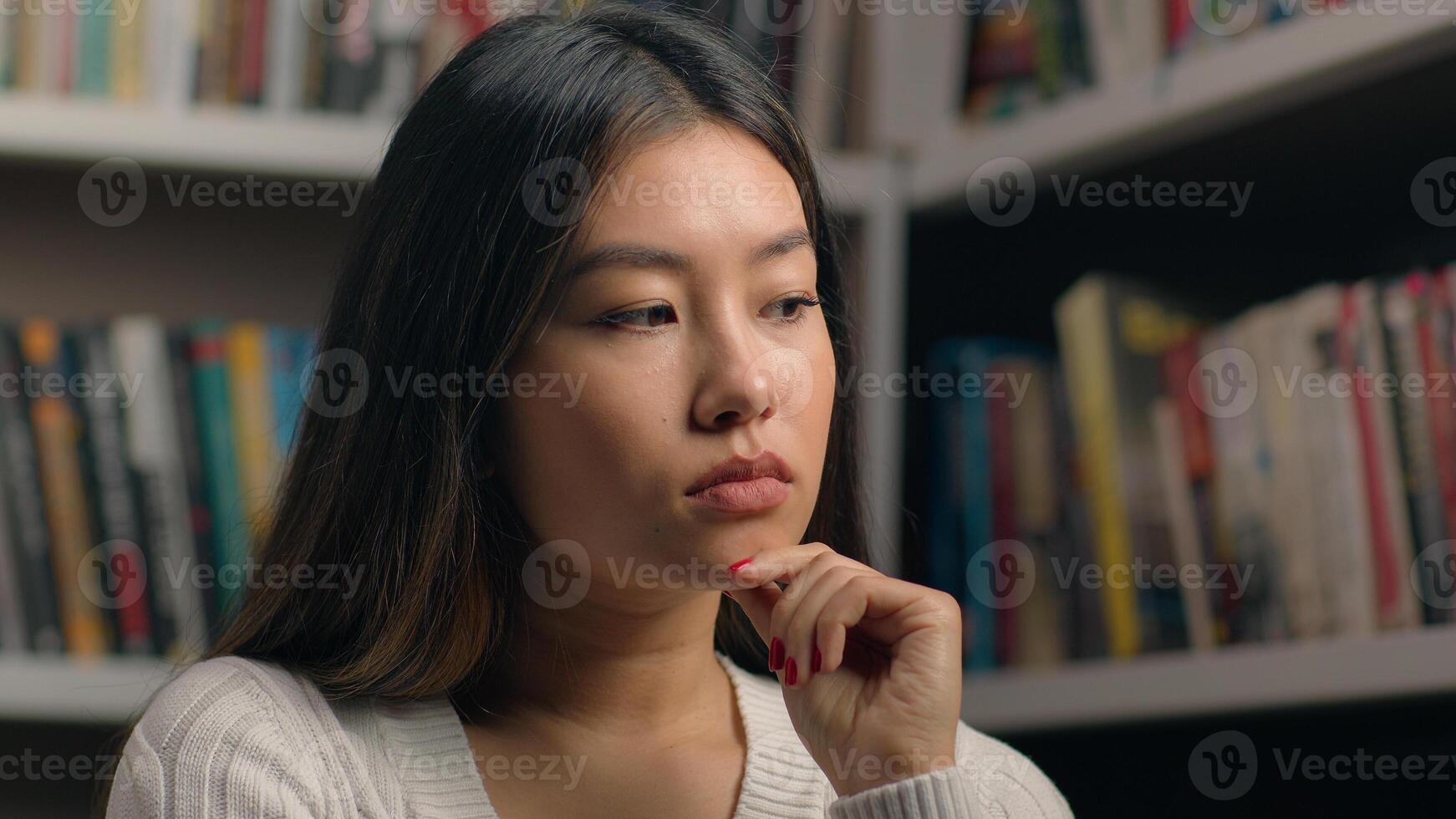 Portrait thoughtful pensive asian business woman girl female student in library near bookshelf ponder deep in thought searching solution in search create new ideas planning analyzing think on answer photo