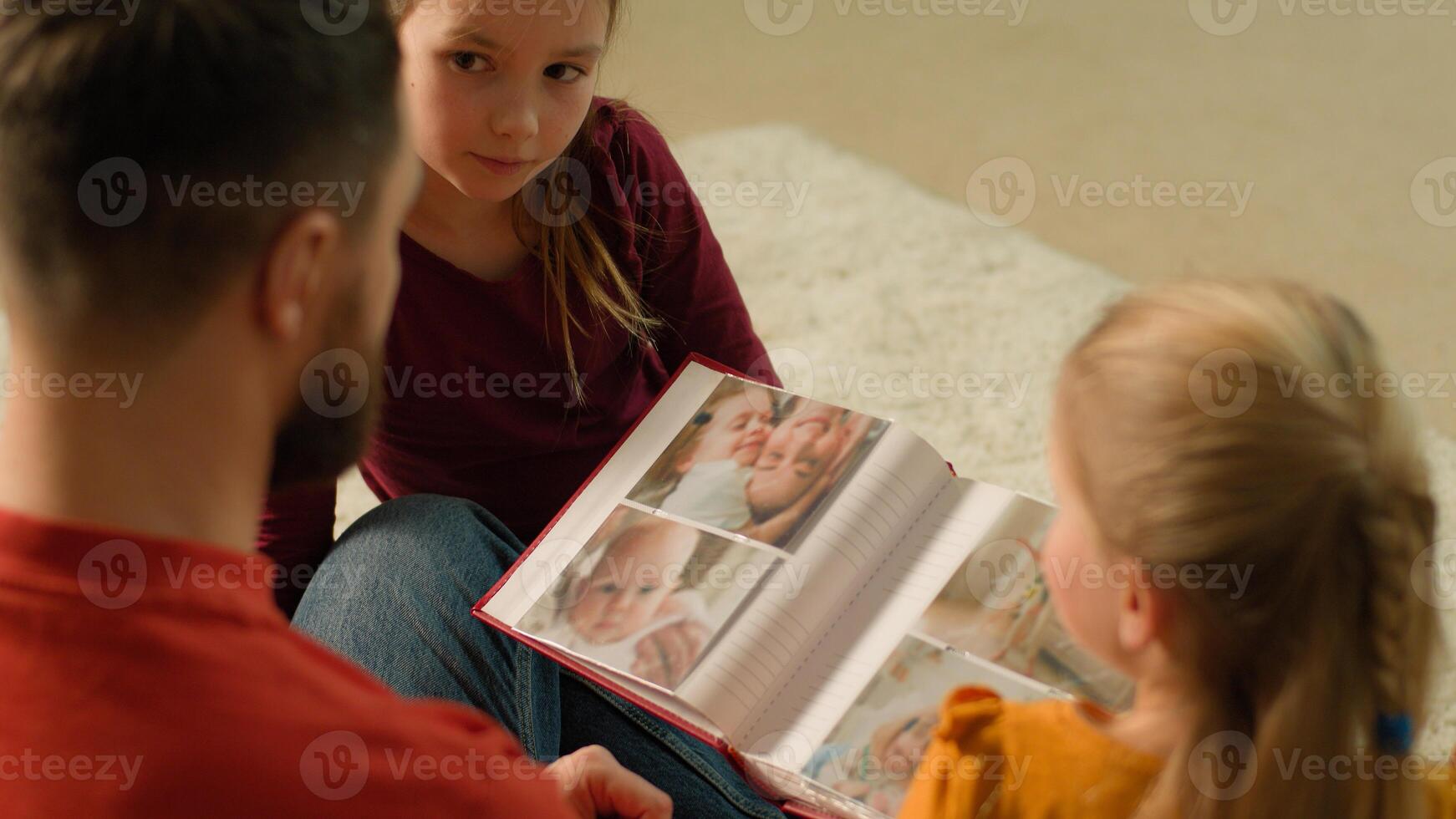 Caucasian parent father and children kids laughing having fun together enjoy evening weekend happy dad daughters babies siblings little girls hold book with funny photos watching family photo album