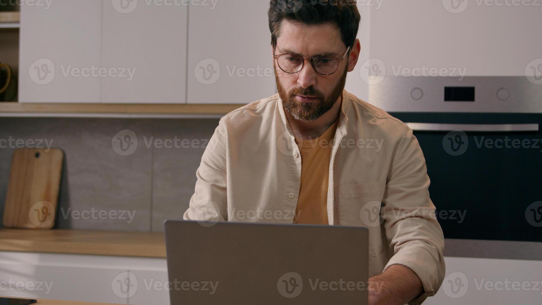 Moving shot Caucasian man 40s male homeowner checking papers documents financial payments utilities busy with paperwork budget mortgage using laptop computer online at kitchen working distant at home photo