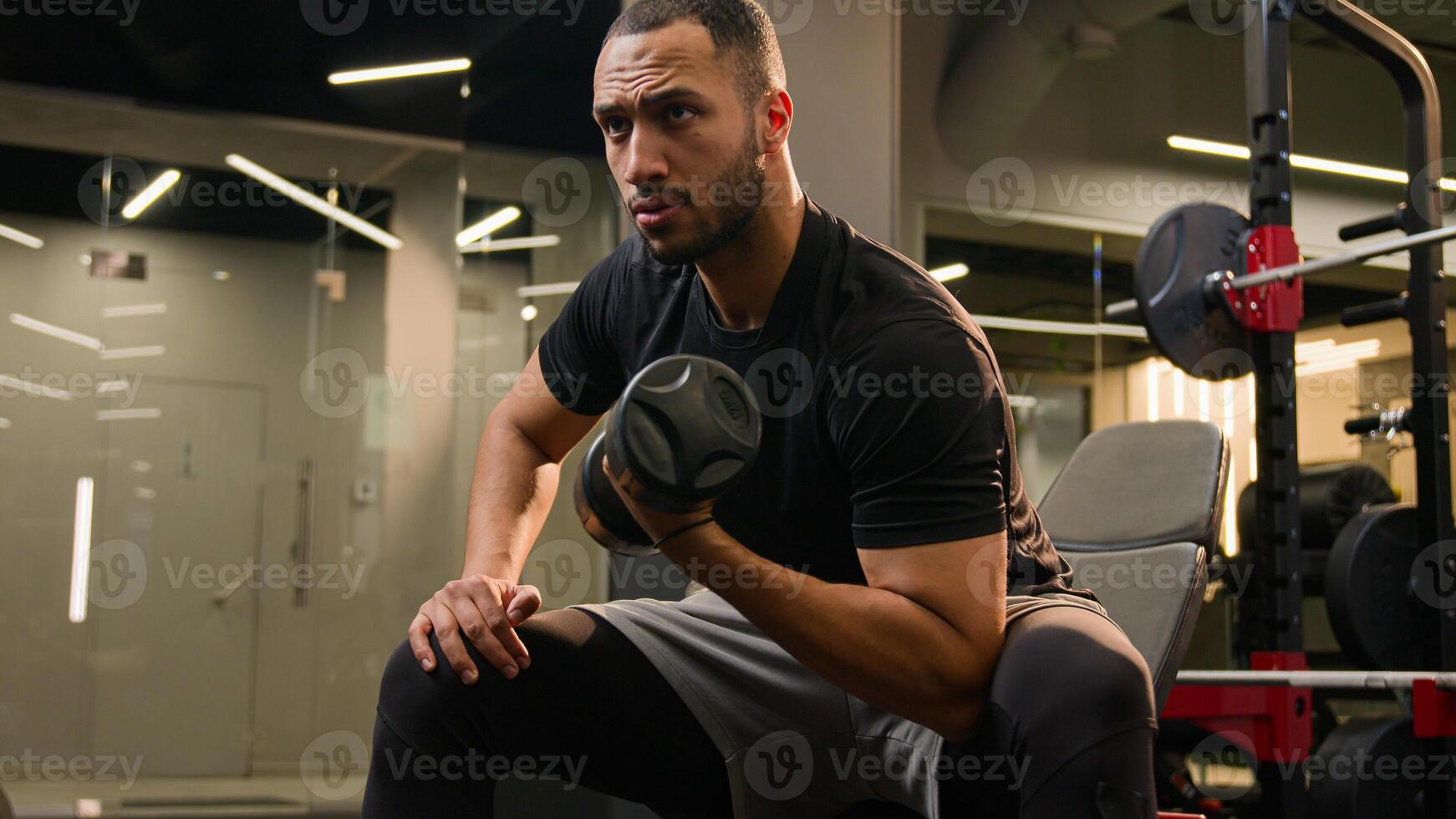 Bodybuilder African American man lifting dumbbell in gym healthy lifestyle fitness guy in sport club strength training exercise powerful workout strong athlete rowing with heavy weights strong arms photo