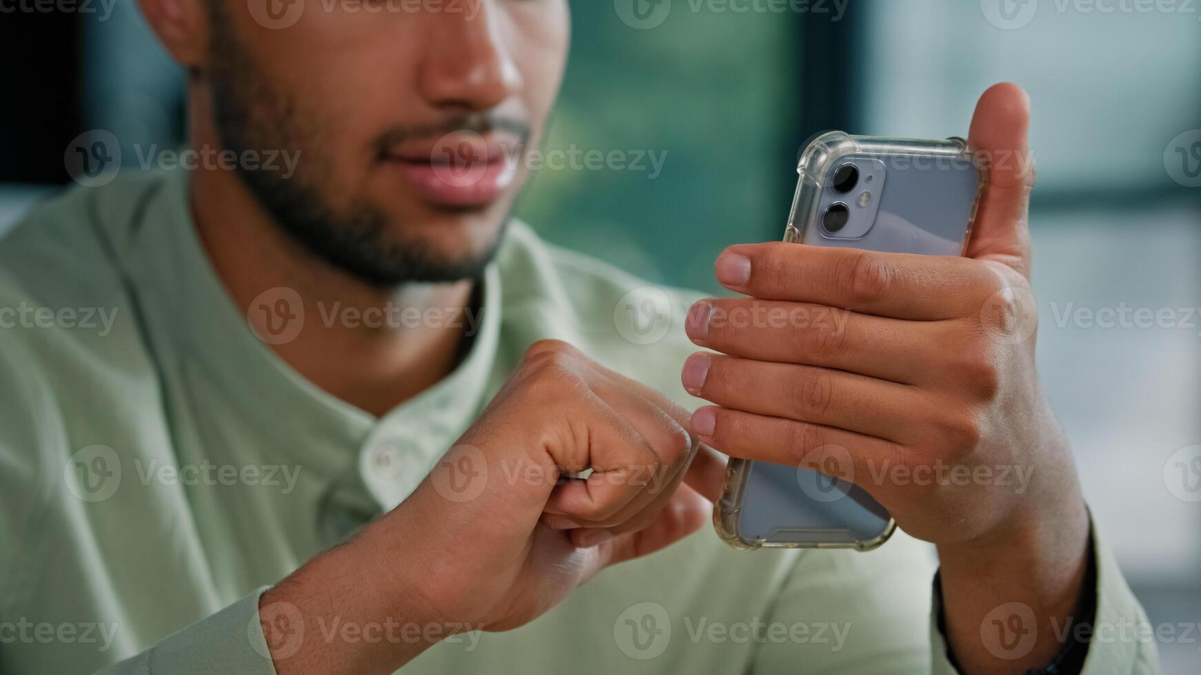 Close up half face African American bearded man indoors male customer businessman holding smartphone sitting at home office using mobile app service scrolling phone screen play game browsing in net photo