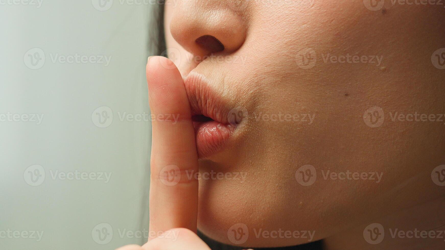 Close up female mouth Asian chinese korean japanese girl unrecognizable woman showing hush lips secret silence quite secrecy confidential mysterious whisper silent hand gesture face details in studio photo