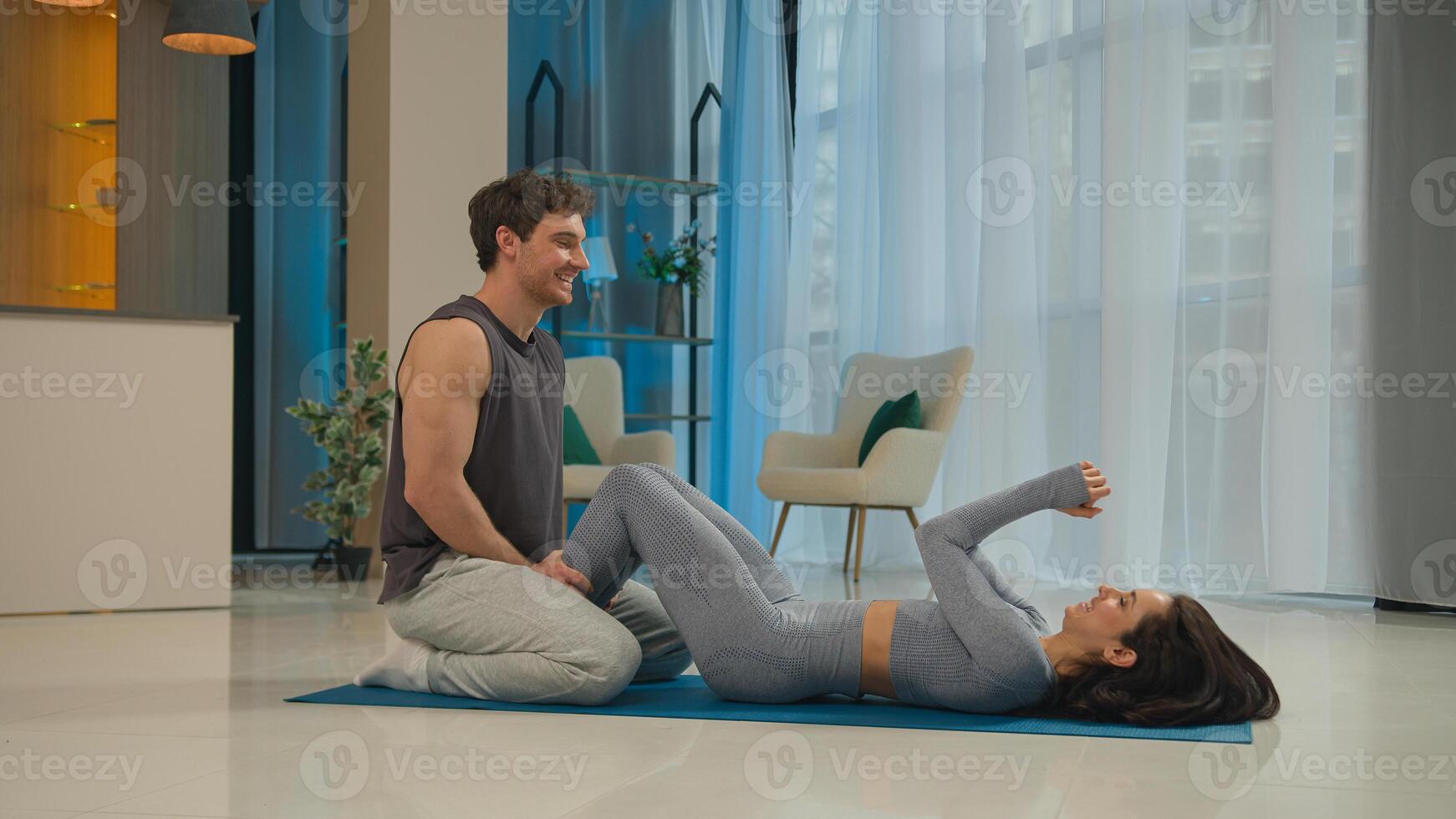 Caucasian couple woman pumping abdominal muscles abs press man helping holding legs achievement sport sportswoman sportsman athletic together give five team coach training exercise activity gymnastic photo