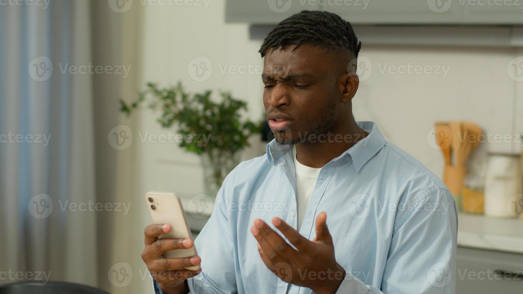 African American man biracial male ethnic guy user at home indignant confused angry bad sms news device problem mobile phone lost app crash smartphone read negative message annoyed gadget trouble spam photo