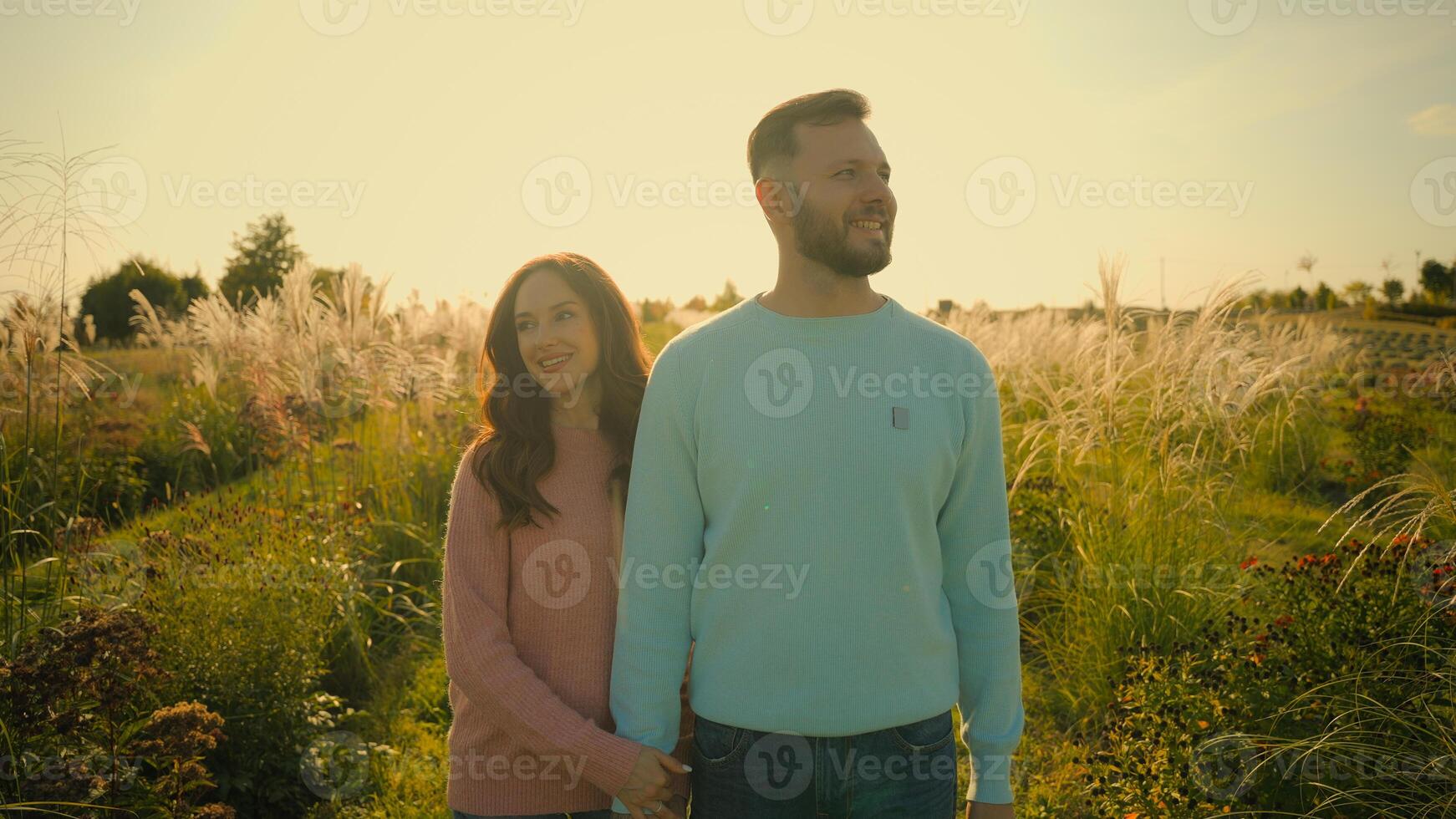 Laughing Caucasian couple female woman girl wife holding hands bearded man male guy husband walking stroll farm field meadow summer weekend happy family girlfriend boyfriend spend time together nature photo