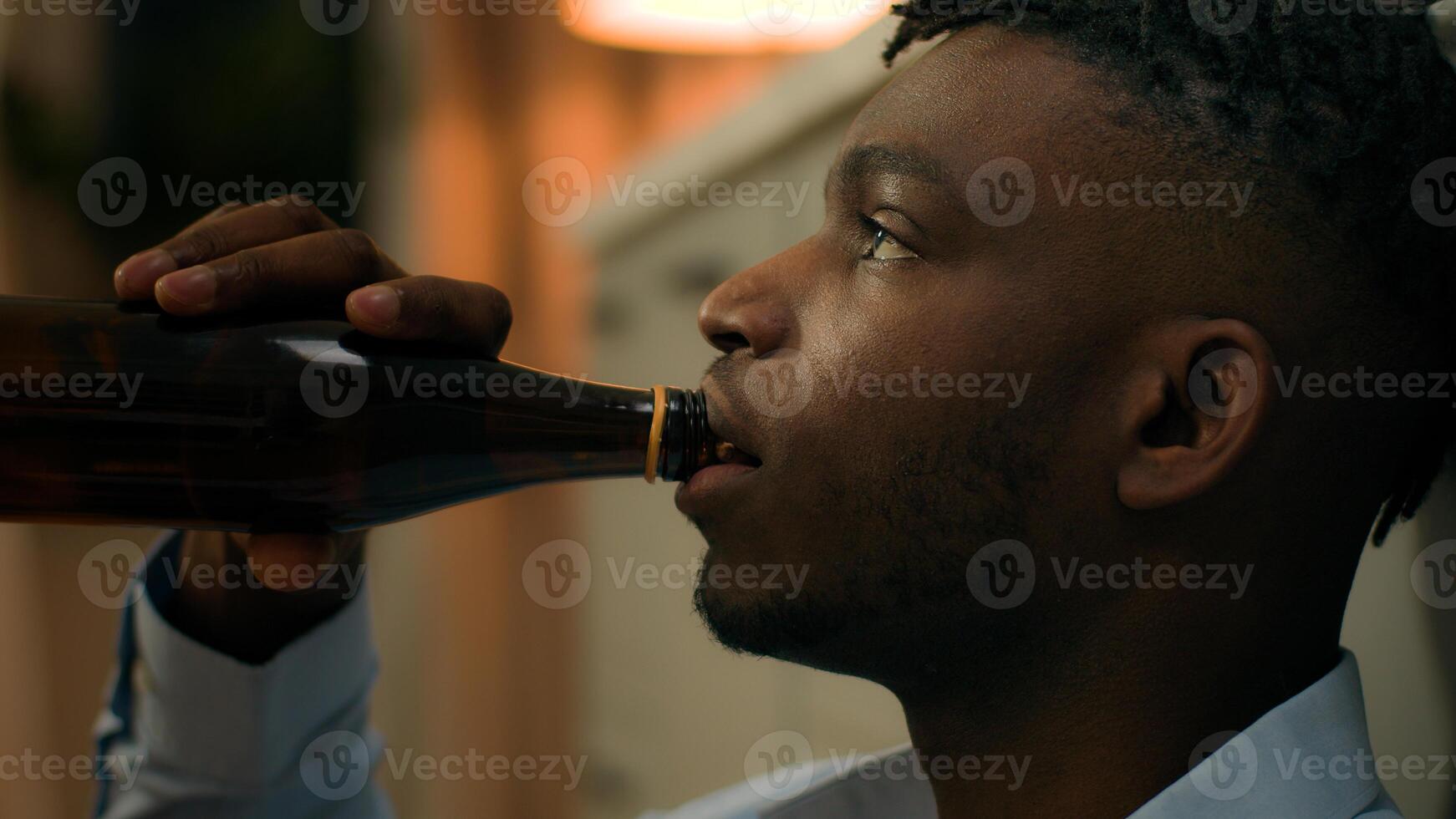 Addicted upset drunk African American depressed stress man drinking alcohol sad suffer problem drink beer with bottle ethnic guy biracial male addiction stressed mental worry bad habit home kitchen photo