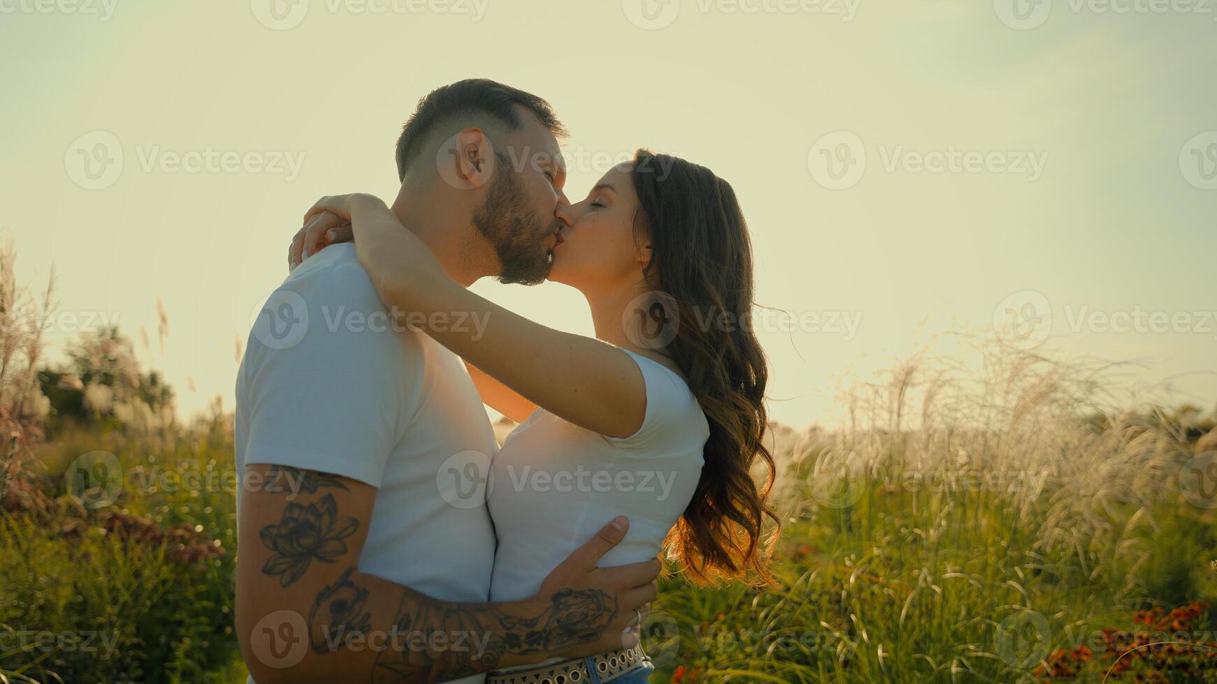 Happy romantic loving Caucasian couple man woman tender family wife husband kiss guy hug girl showing love hugging embracing kissing outdoors deserted wheat field sunrise sunshine dating relationship photo