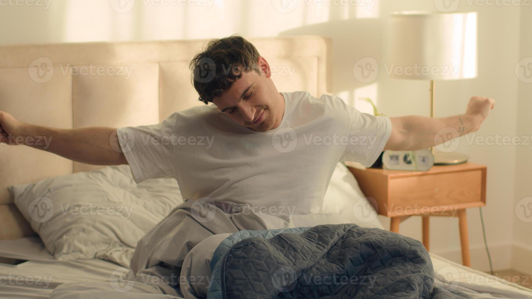 Caucasian man waking up stretching sleeping good morning bed bedroom home smiling satisfaction enjoy male weekend cozy daydream slumber napping tenant homeowner relaxed pulling pleasure apartment guy photo