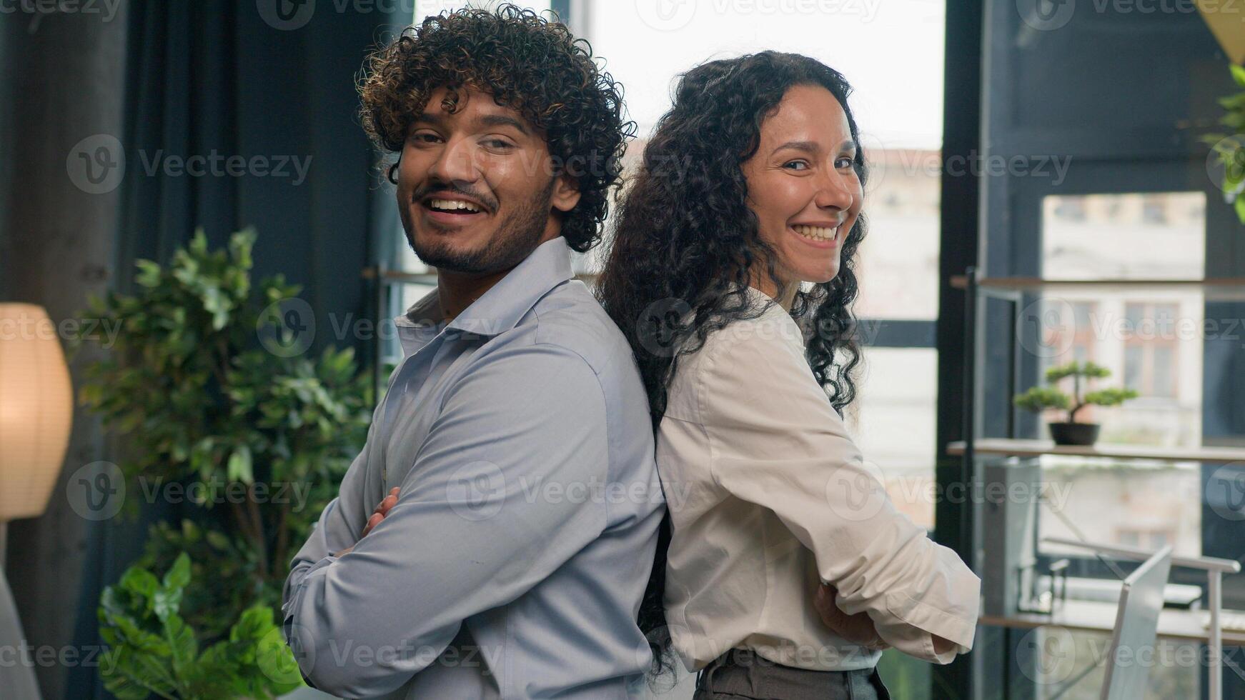 Two business partners multiracial colleagues Arabian man businessman and Hispanic woman businesswoman posing arms crossed in office diverse managers team leaders happy smiling partnership cooperation photo