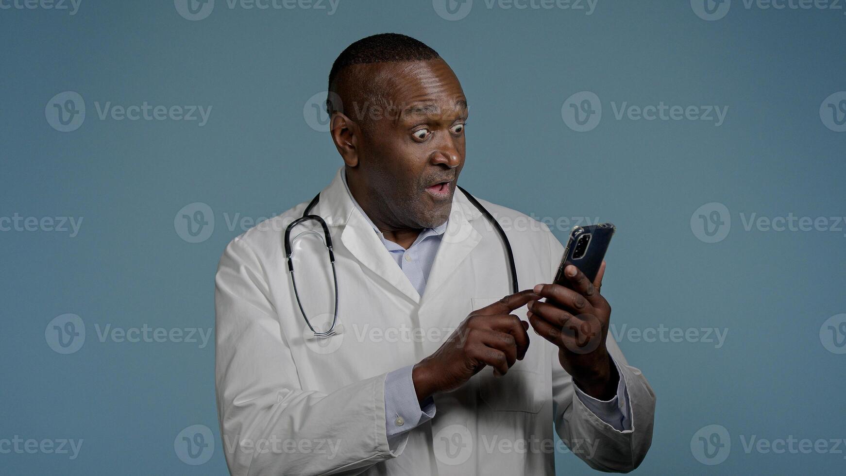 African American man doctor receive sms message on mobile phone reading good news from patient smiling male medical employee celebrating victory rejoicing success recovery excellent analysis results photo