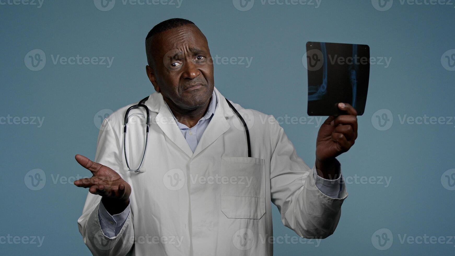Mature serious man radiologist doctor examining x-ray check results scan looking pensive and focused upset male medic expert surgeon analyzes injury on tomography image makes bad diagnosis fracture photo
