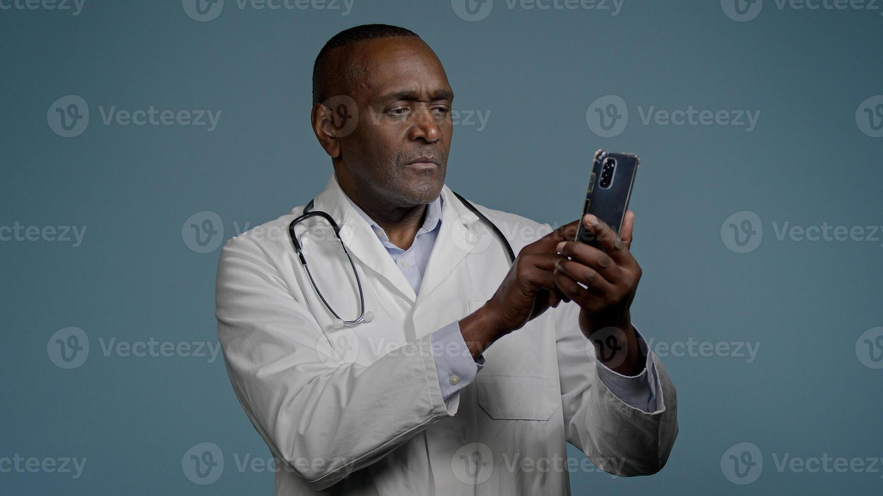 African American man male doctor in white uniform typing answer sending email message on smartphone browsing patient card using medical virtual application on mobile phone medicine and modern tech photo