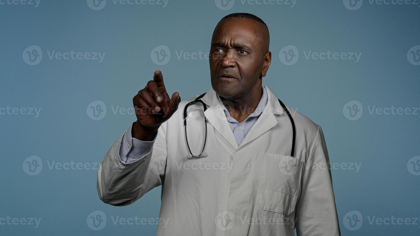 Focused african american man doctor male professional medical worker healthcare employee in blue studio move hands in air imitating work on 3D hologram diagnostics using modern innovative technology photo